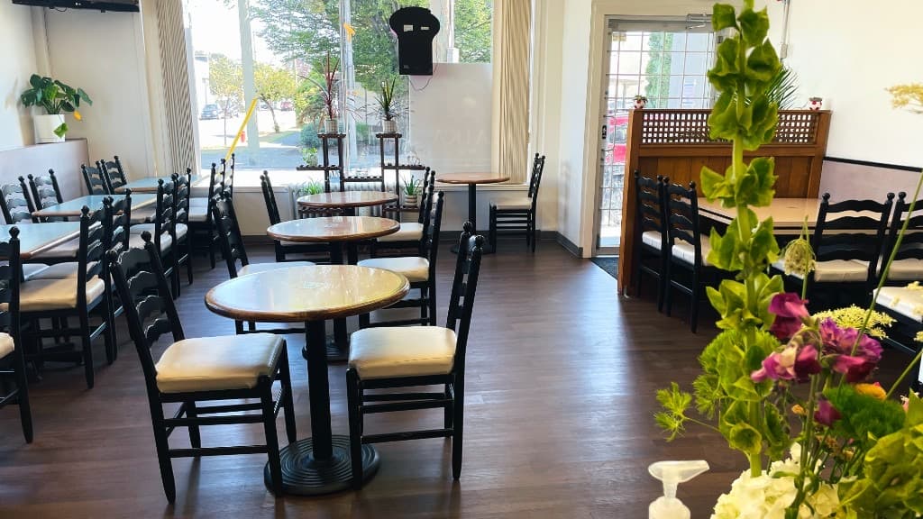 Bright Zaika dining room with round tables, plants, and natural light from the street windows