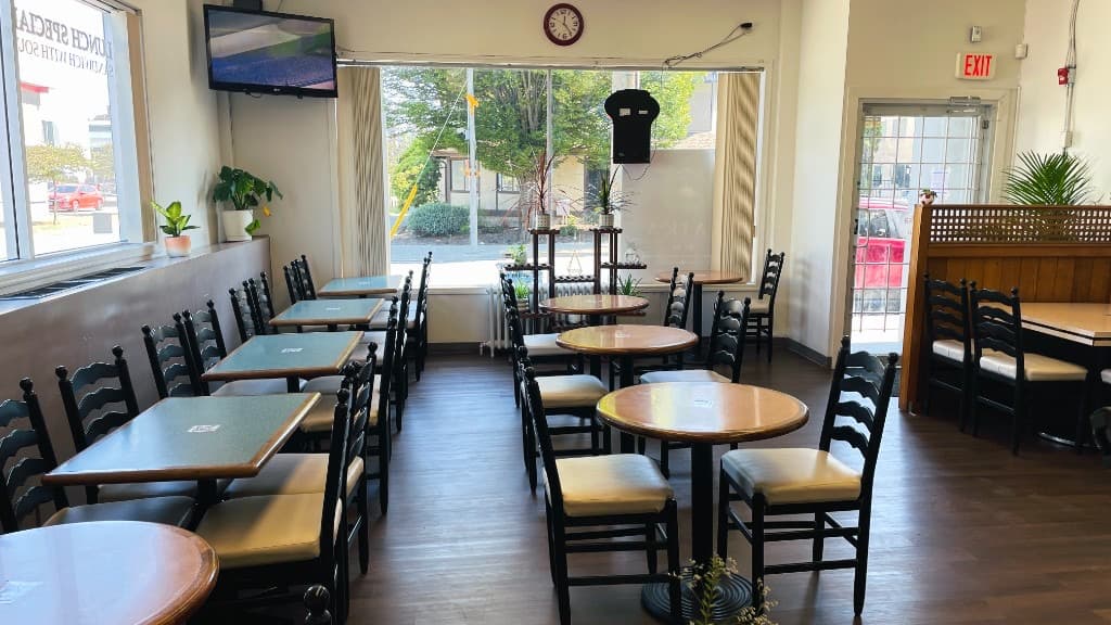 Zaika interior with round and rectangular tables, indoor plants, and large windows